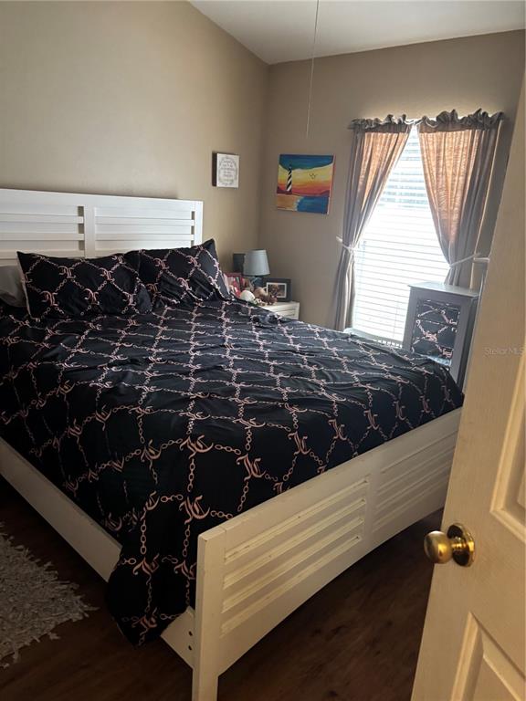 A bedroom features a white bed frame, a patterned black comforter, and a window with curtains — 27450 SUGAR LOAF DRIVE, WESLEY CHAPEL, FL