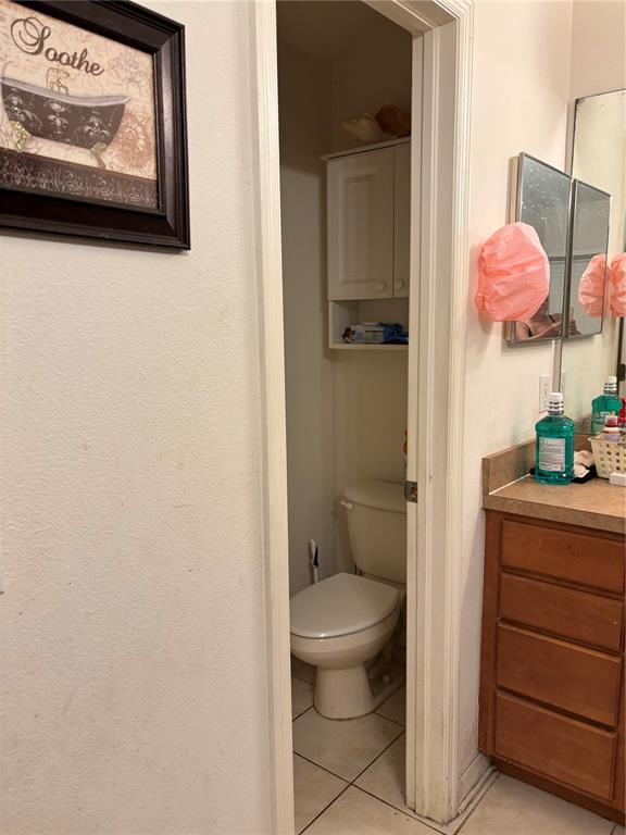 A bathroom features a toilet in a small alcove next to a wooden vanity — 27450 SUGAR LOAF DRIVE, WESLEY CHAPEL, FL