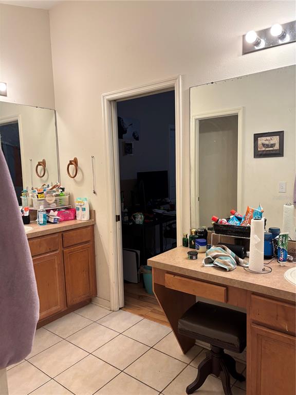 A bathroom features dual vanities with wood cabinets, tiled flooring, and a central doorway — 27450 SUGAR LOAF DRIVE, WESLEY CHAPEL, FL