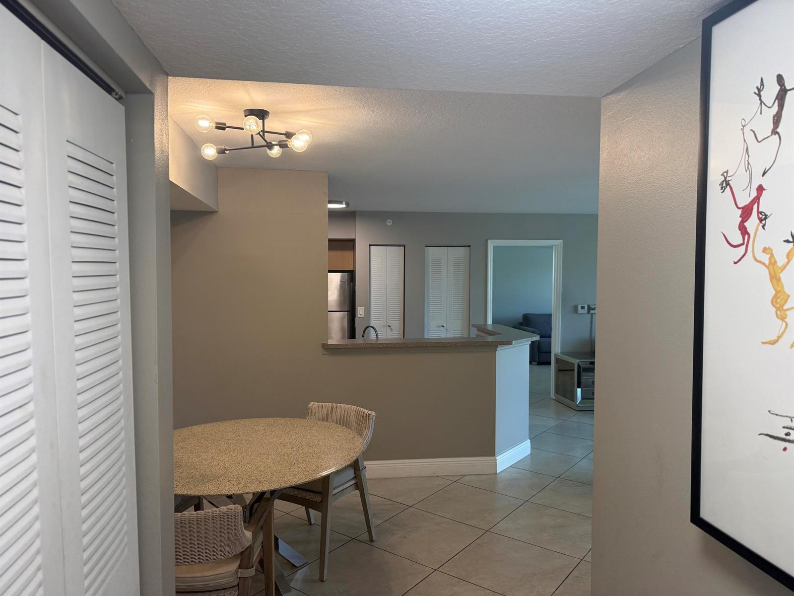 A dining area with a round table sits in front of an open kitchen counter — 902 Villa Circle, Boynton Beach FL 33435, BOYNTON BEACH, FL