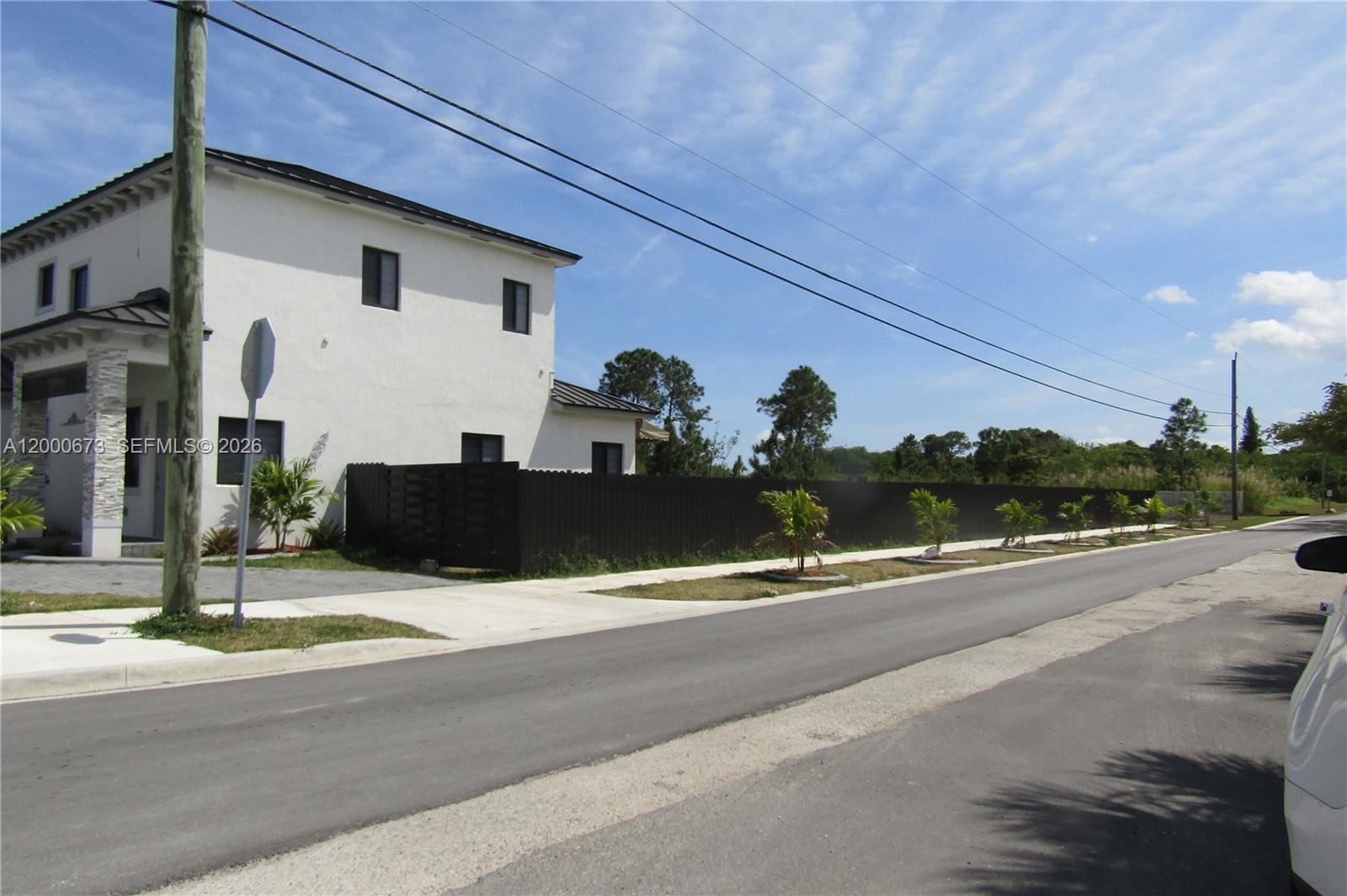 A two-story white house stands next to a vacant lot enclosed by a dark fence — 11998 SW 232nd St, Miami FL 33170, MIAMI, FL