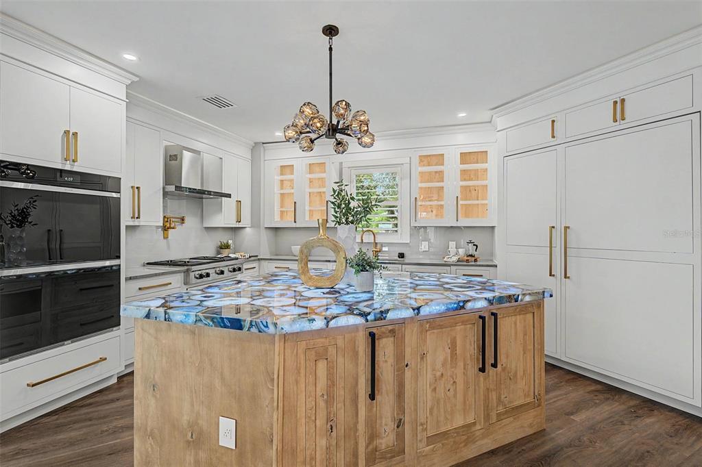 A kitchen features white cabinetry, a wood-toned island with a blue agate countertop, and pendant lighting — 3781 EXECUTIVE DRIVE, PALM HARBOR, FL
