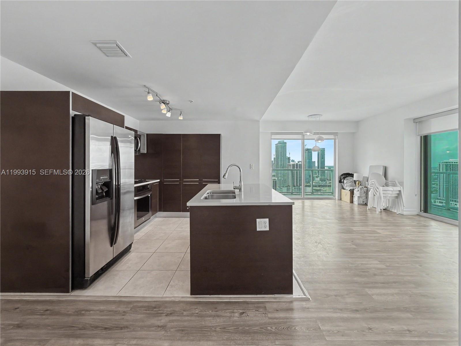A modern kitchen with dark cabinetry and a central island overlooks a city skyline view — 1900 N Bayshore Dr # 3811, Miami FL 33132, MIAMI, FL