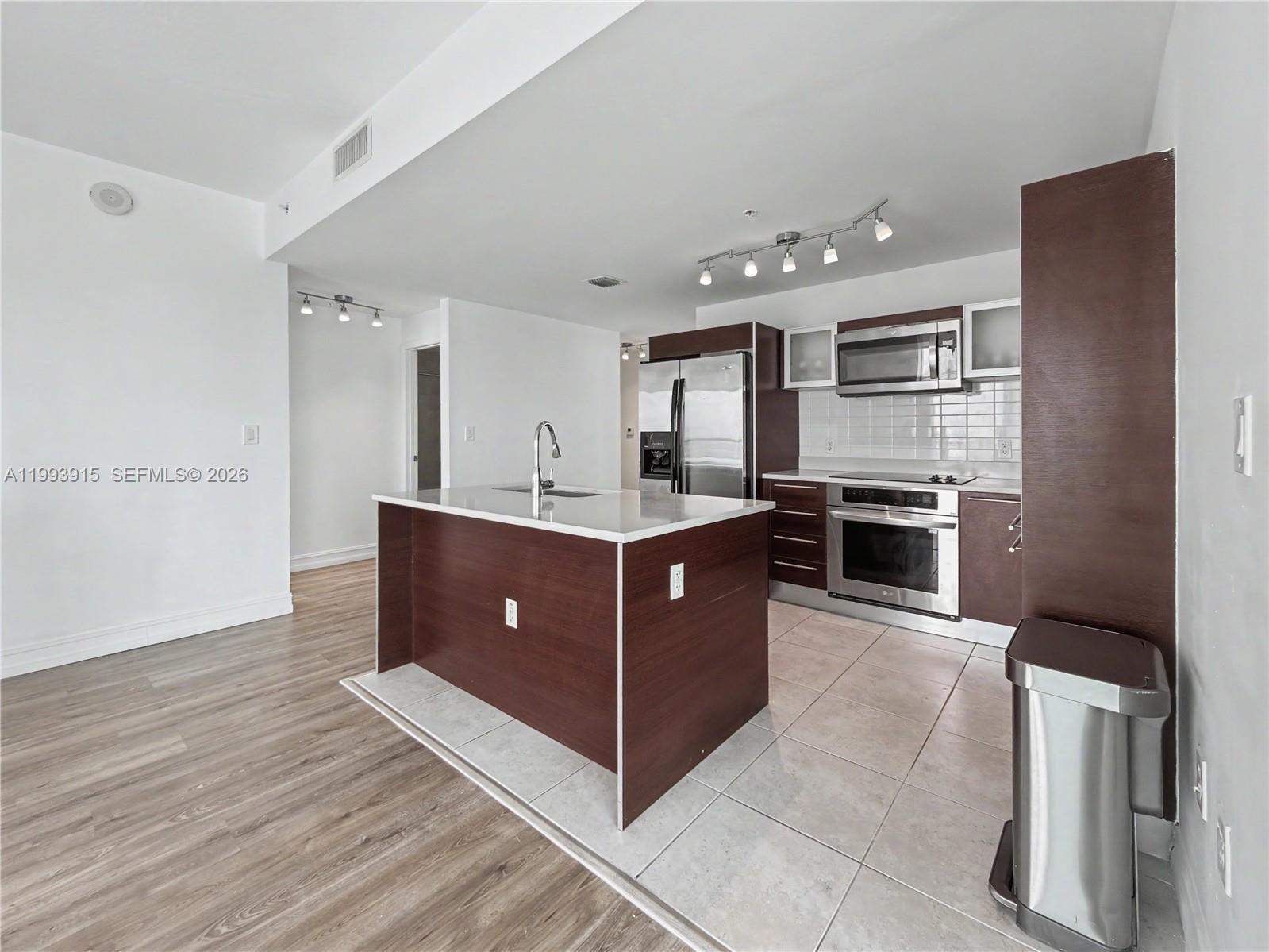 A modern kitchen features dark wood cabinetry, stainless steel appliances, and a central island — 1900 N Bayshore Dr # 3811, Miami FL 33132, MIAMI, FL
