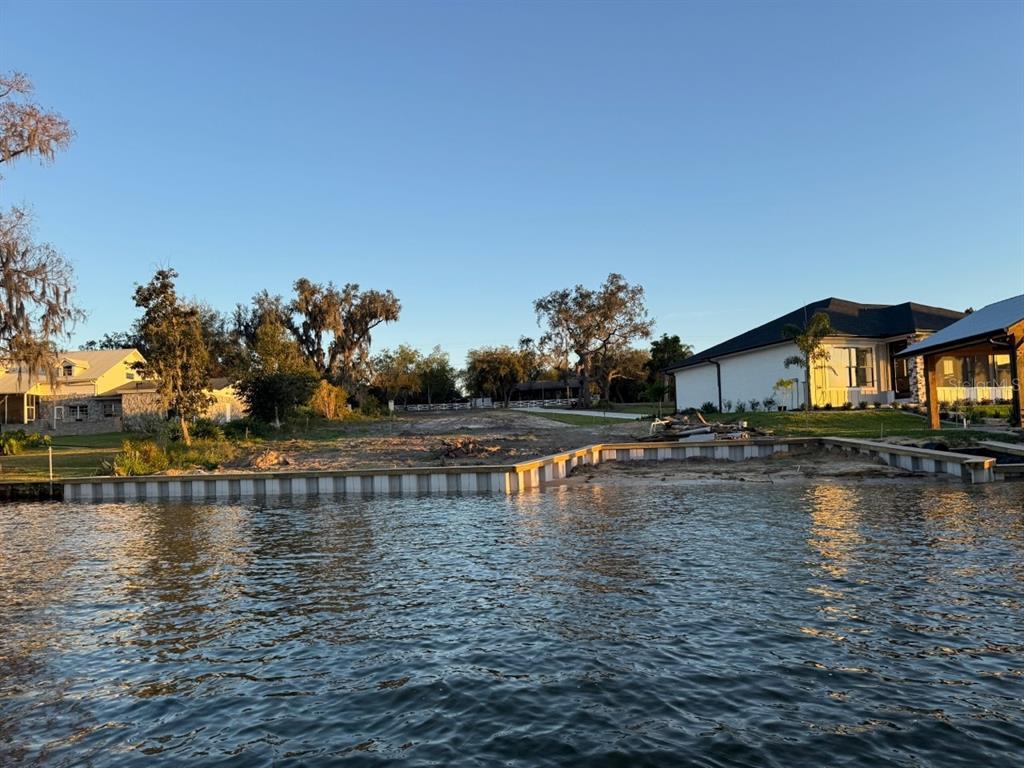 A vacant waterfront lot features a newly installed vinyl seawall and sandy shoreline — 1232 CR 17 ROAD N, LAKE PLACID, FL