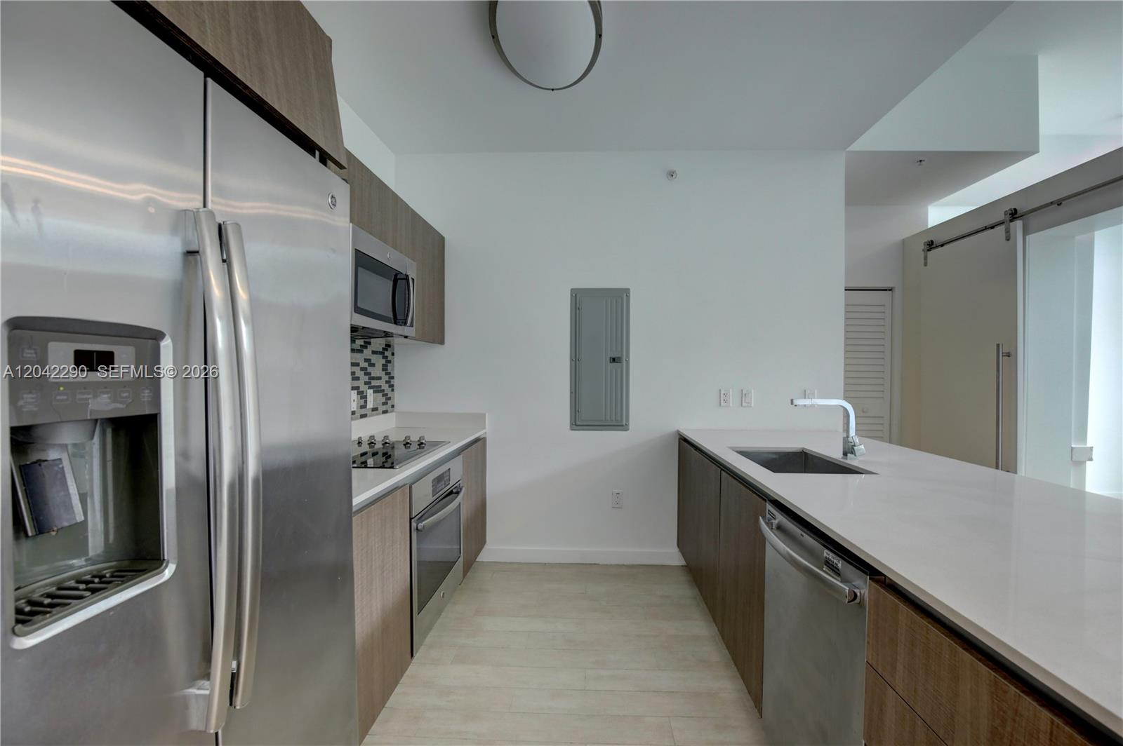 A modern kitchen features stainless steel appliances, wood-toned cabinetry, and a white quartz countertop island — 1600 SW 1st Ave # 09, Miami FL 33129, MIAMI, FL