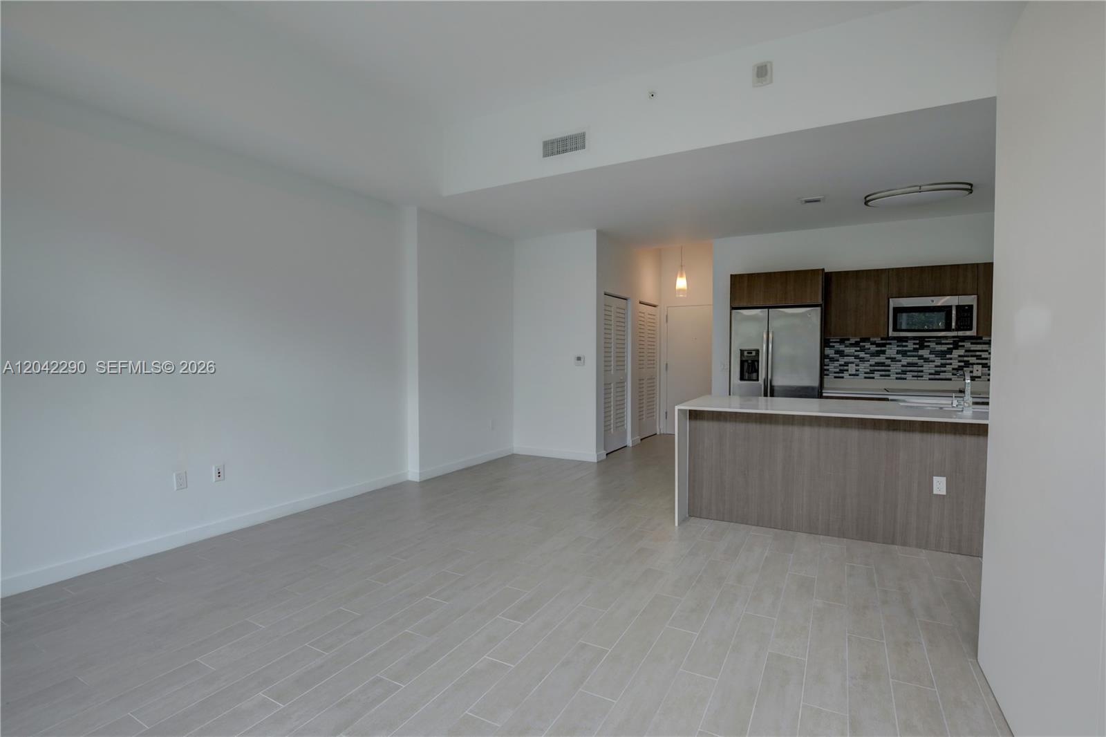 An open-concept living area features light tile flooring, white walls, and a modern kitchen — 1600 SW 1st Ave # 09, Miami FL 33129, MIAMI, FL