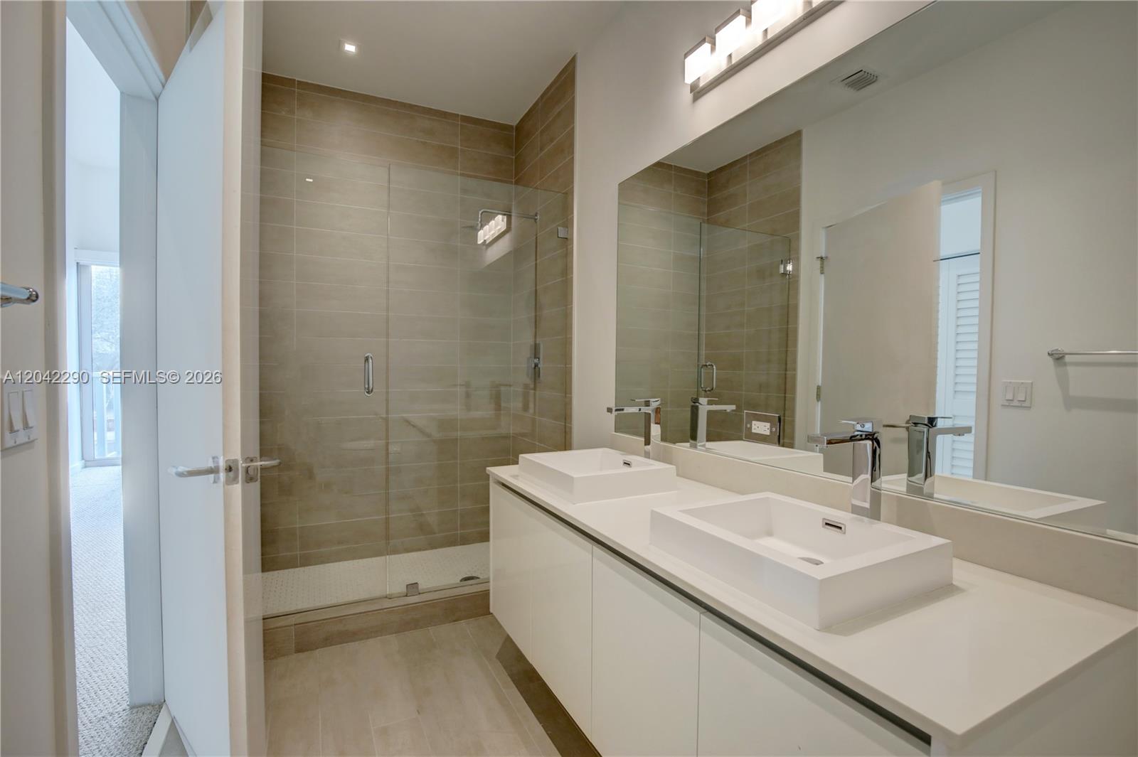 A modern bathroom features a glass-enclosed shower, double vessel sinks, and white cabinetry — 1600 SW 1st Ave # 09, Miami FL 33129, MIAMI, FL