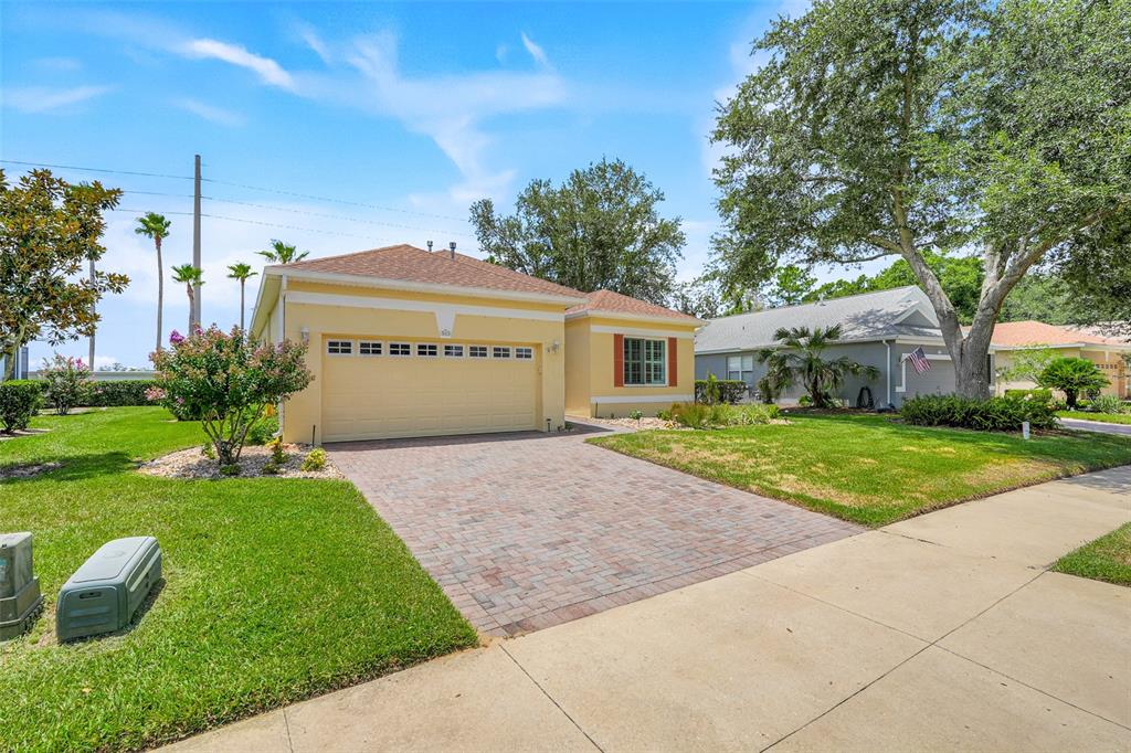 A yellow single-story house with a brick paver driveway and a two-car garage — 3003 PINNACLE COURT, CLERMONT, FL