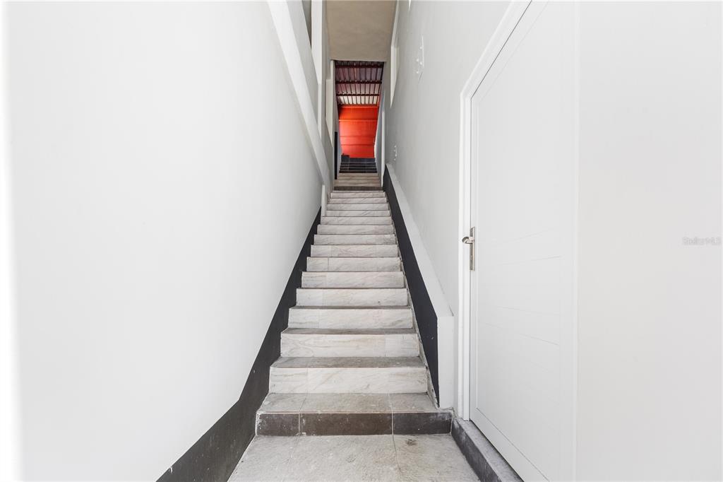 A narrow indoor staircase with light-colored steps leads upward between two white walls — 21 EDUARDO CONDE, SAN JUAN, PR