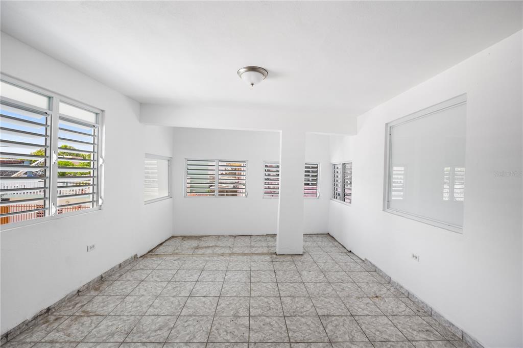 An empty room with white walls, tiled floors, and multiple louvered windows — 21 EDUARDO CONDE, SAN JUAN, PR