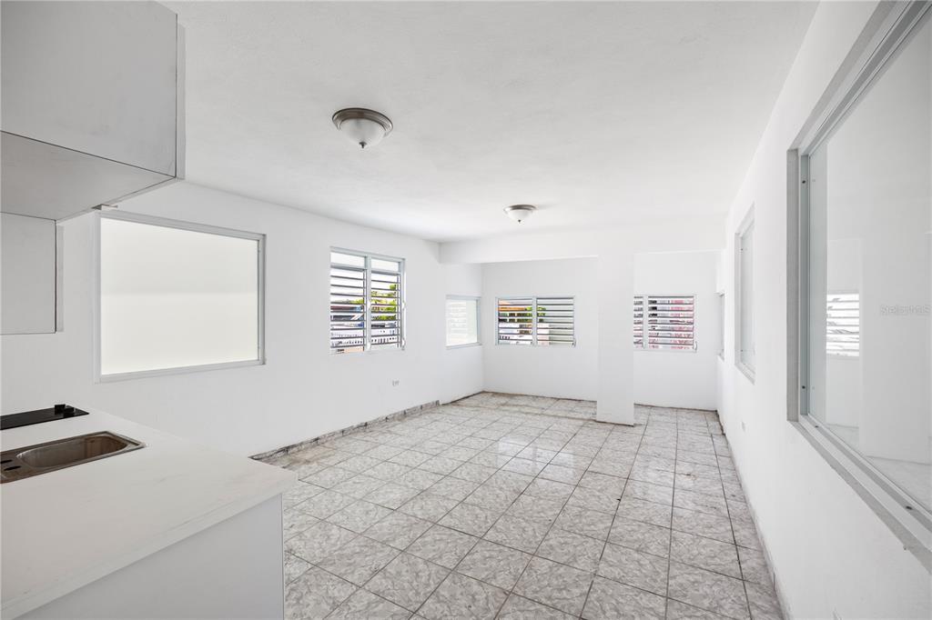 An empty room with white walls, tiled floors, and several windows with metal security bars — 21 EDUARDO CONDE, SAN JUAN, PR
