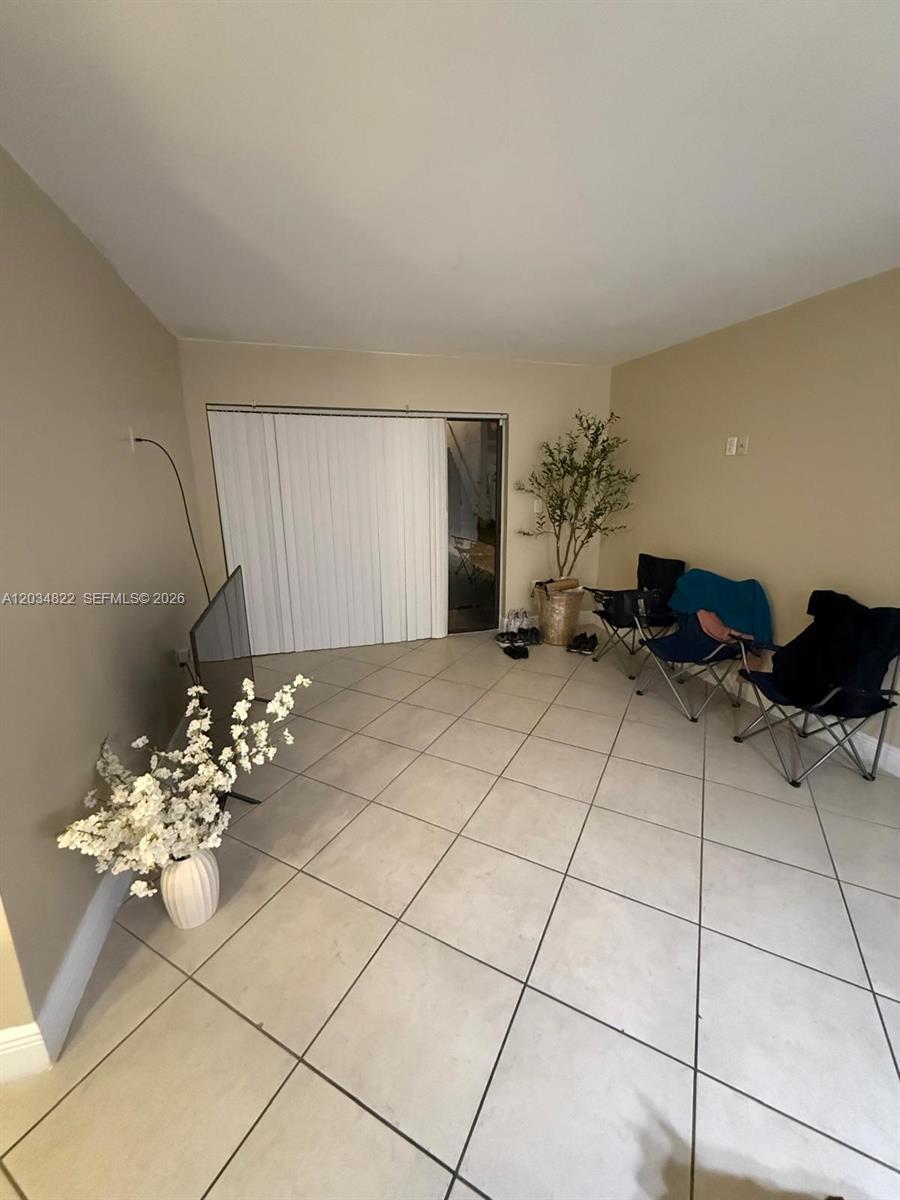 This room features light-colored tile flooring, a sliding glass door, and portable folding chairs — 7405 SW 152nd Ave # 107, Miami FL 33193, MIAMI, FL