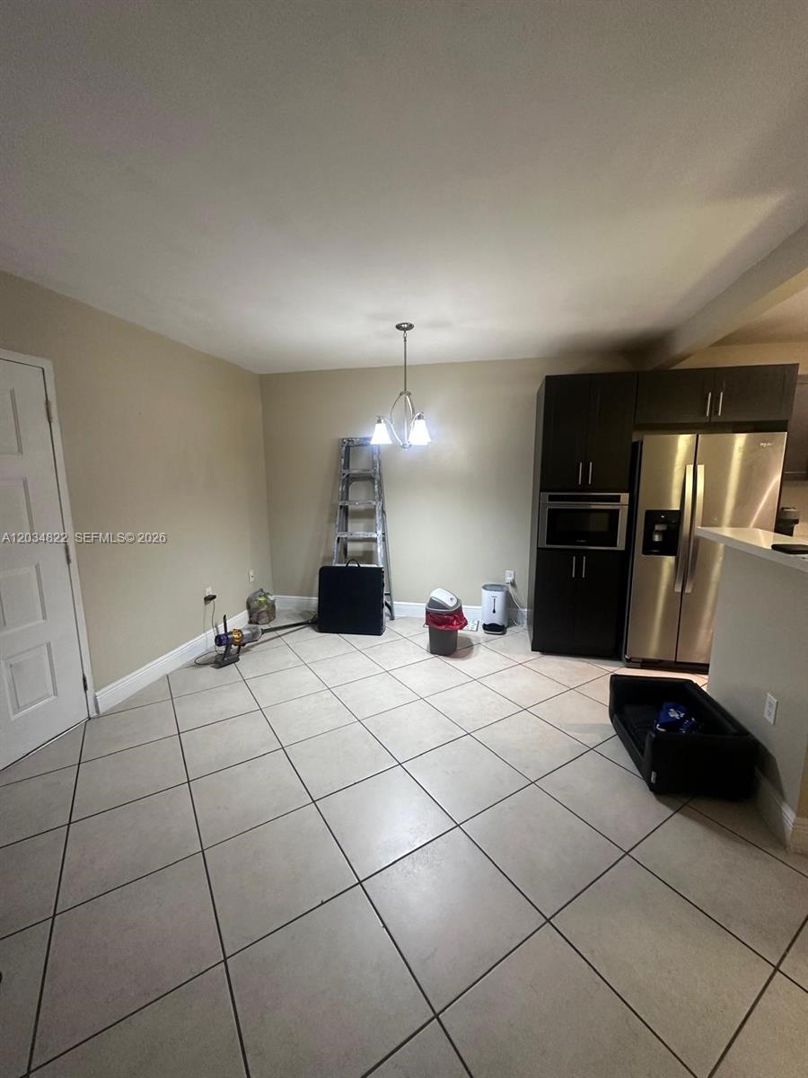 This kitchen and dining area features tile flooring, dark cabinetry, and stainless steel appliances — 7405 SW 152nd Ave # 107, Miami FL 33193, MIAMI, FL