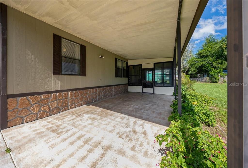 A covered concrete patio features a stone-patterned base and a screened-in entrance area — 14716 SE 90TH TERRACE, SUMMERFIELD, FL