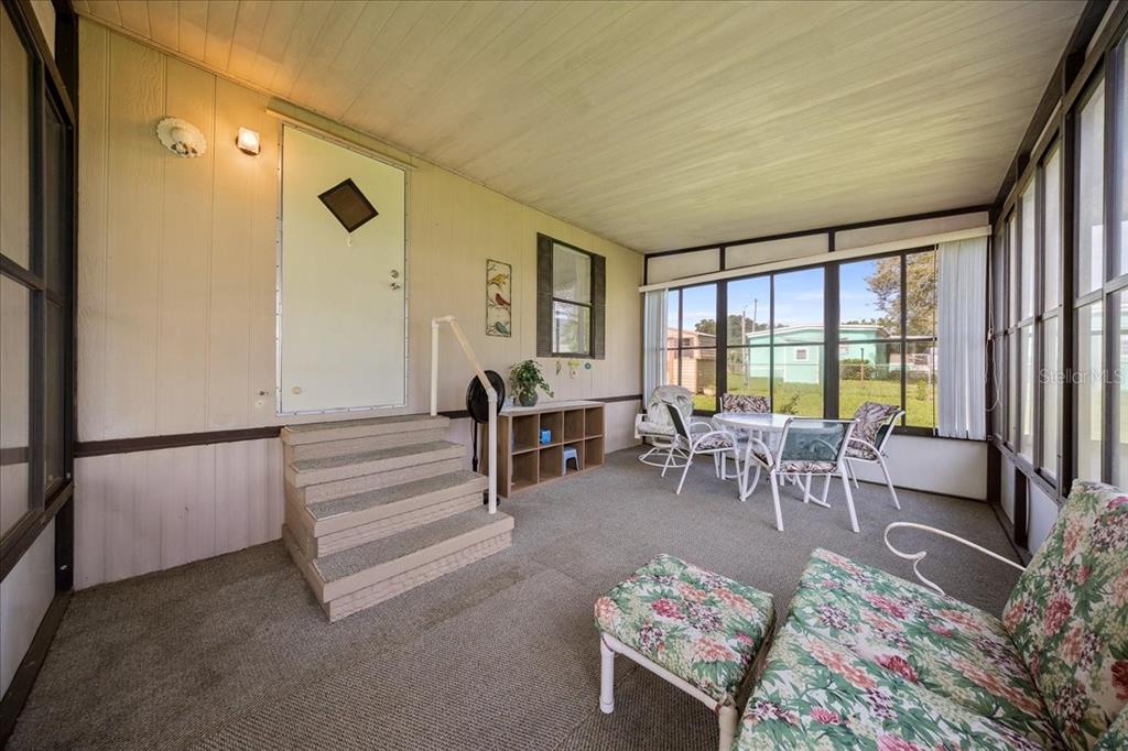 A screened-in porch with carpeted flooring, a set of stairs, and outdoor furniture — 14716 SE 90TH TERRACE, SUMMERFIELD, FL