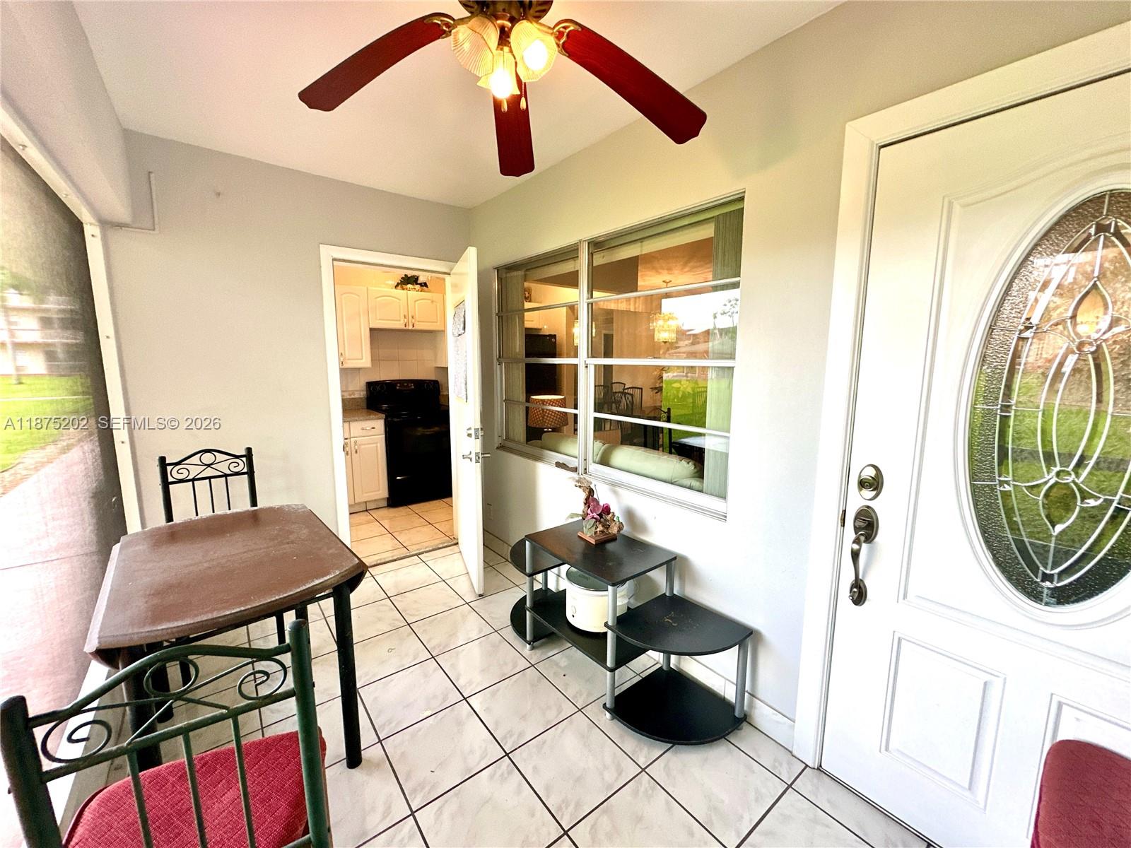 A tiled sunroom features a ceiling fan, a dining set, and a view into the kitchen — 5300 Washington St # A139, Hollywood FL 33021, HOLLYWOOD, FL