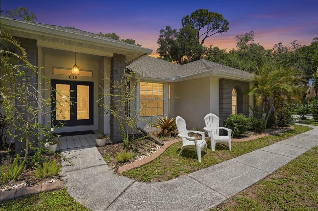 The exterior of a single-story house features a front entrance, walkway, and two white chairs — 610 WOODVIEW WAY, BRADENTON, FL