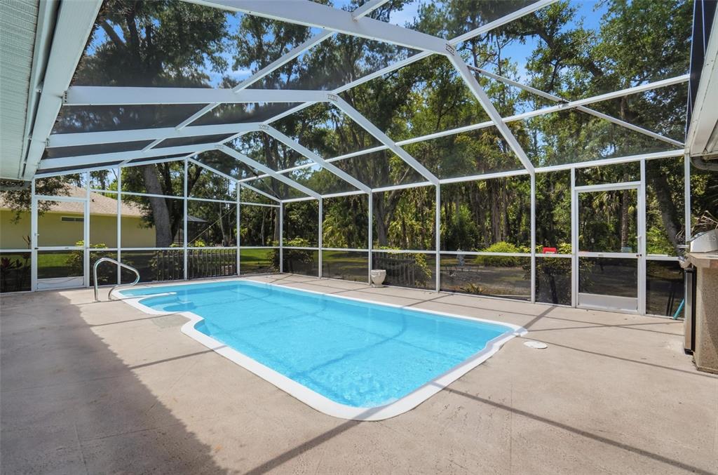 A rectangular swimming pool is enclosed by a white screen cage on a concrete patio — 610 WOODVIEW WAY, BRADENTON, FL