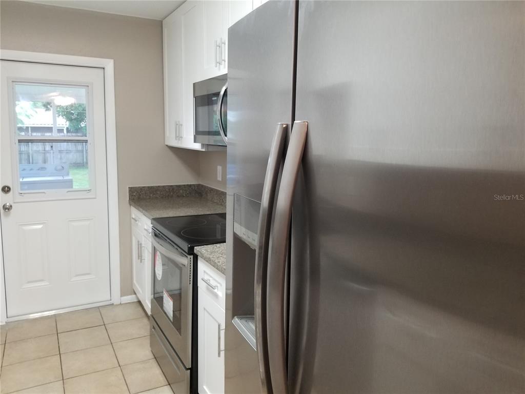 A kitchen features stainless steel appliances, white cabinets, and a door leading to the outdoors — 11231 PENDLETON AVENUE UNIT 2, ENGLEWOOD, FL