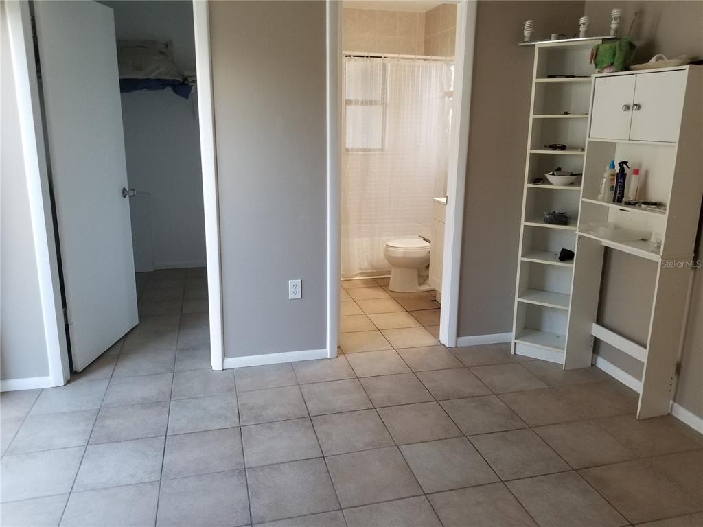 A room with tiled flooring, a closet, and an adjacent bathroom with a shower curtain — 11231 PENDLETON AVENUE UNIT 2, ENGLEWOOD, FL
