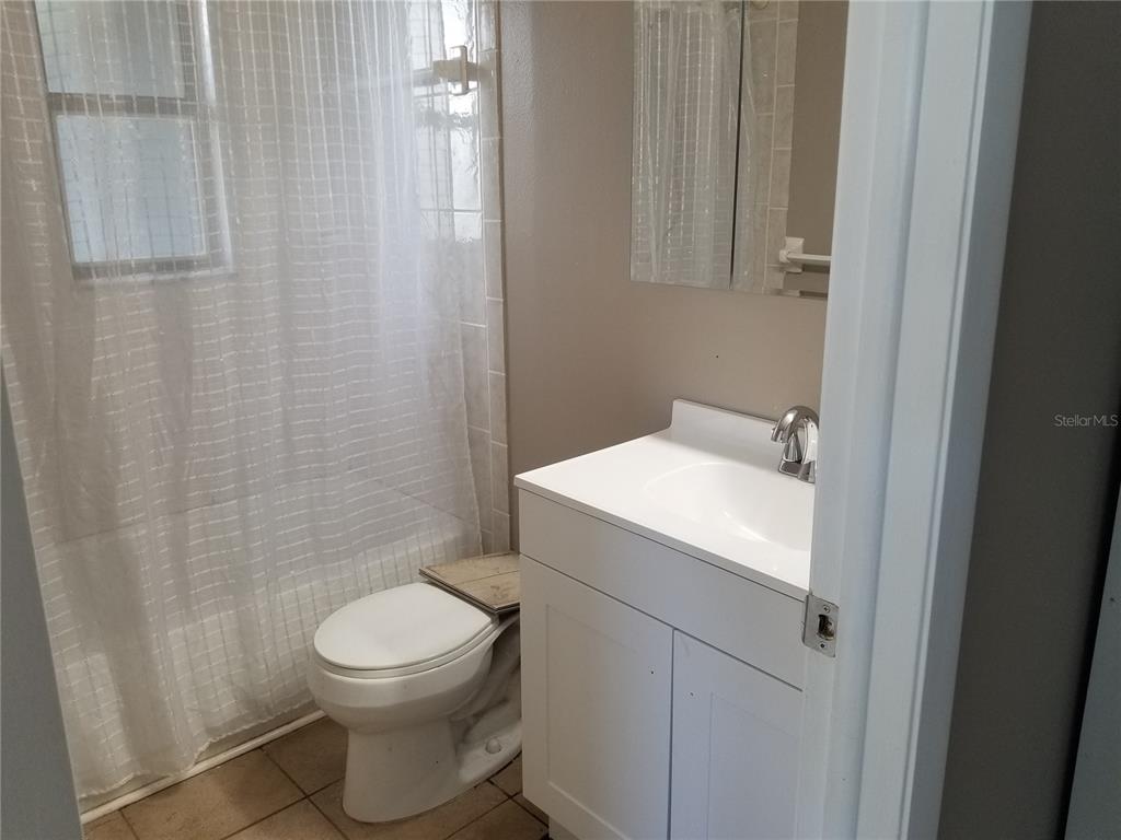 A small bathroom features a white vanity, a toilet, and a shower with a curtain — 11231 PENDLETON AVENUE UNIT 2, ENGLEWOOD, FL