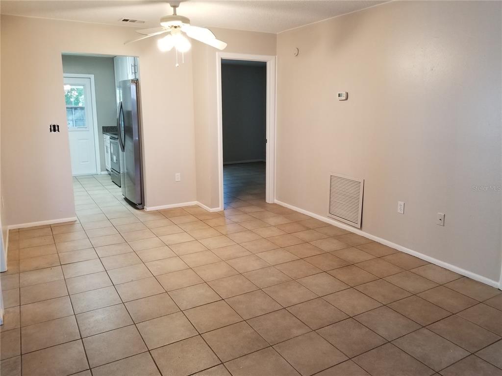 A tiled dining area features a ceiling fan, a doorway to the kitchen, and beige walls — 11231 PENDLETON AVENUE UNIT 2, ENGLEWOOD, FL