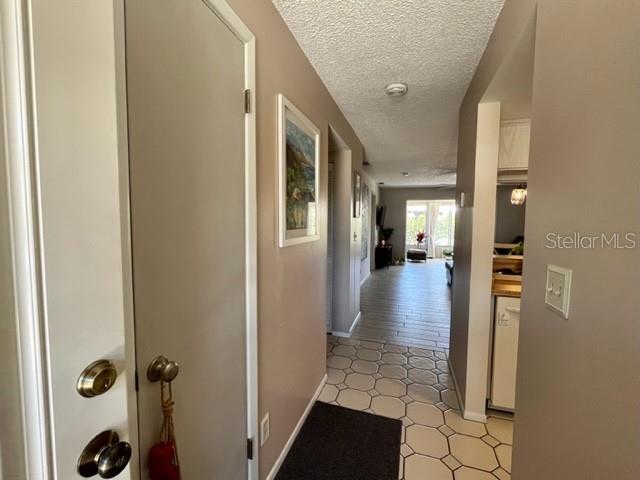 An interior hallway features light-colored walls, tile flooring, and a view toward a bright room — 9616 MIDIRON COURT, NEW PORT RICHEY, FL