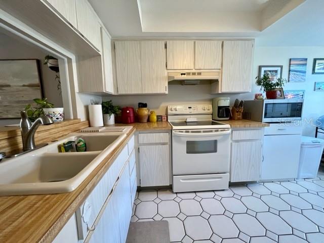 A kitchen features light wood-grain cabinets, a white stove, and a white tiled floor — 9616 MIDIRON COURT, NEW PORT RICHEY, FL