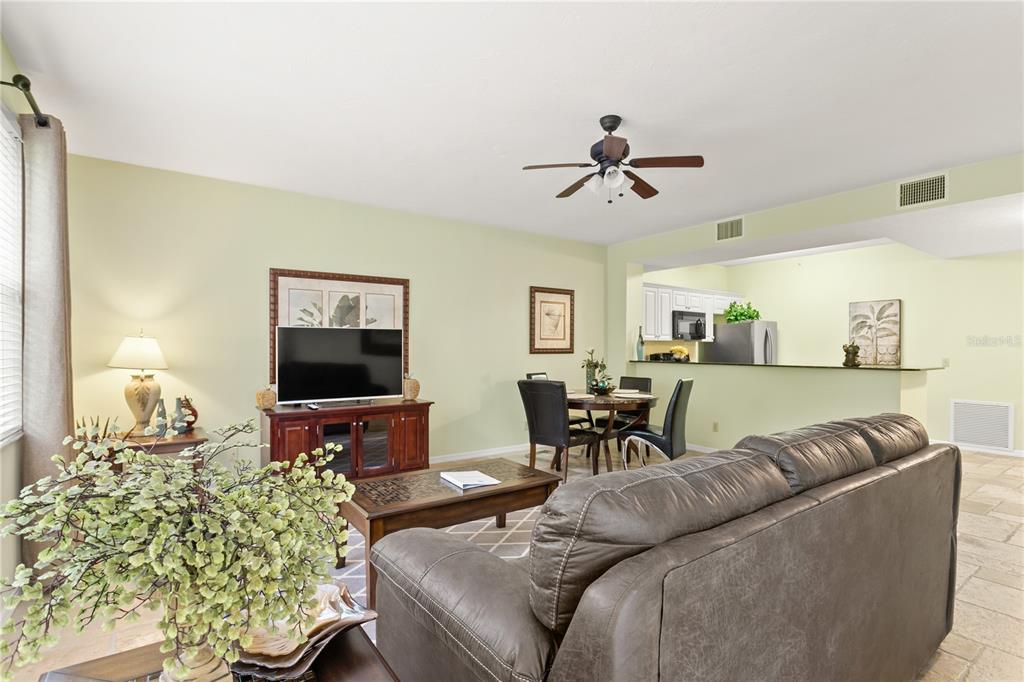 A living room with a brown leather sofa, television, and dining area near a kitchen — 3506 54TH DRIVE W UNIT 108, BRADENTON, FL