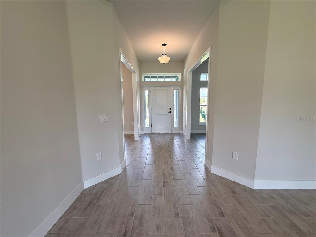 A bright entryway features light wood-look tile flooring, white trim, and a central pendant light — 10443 SUNBURY DRIVE, PORT CHARLOTTE, FL