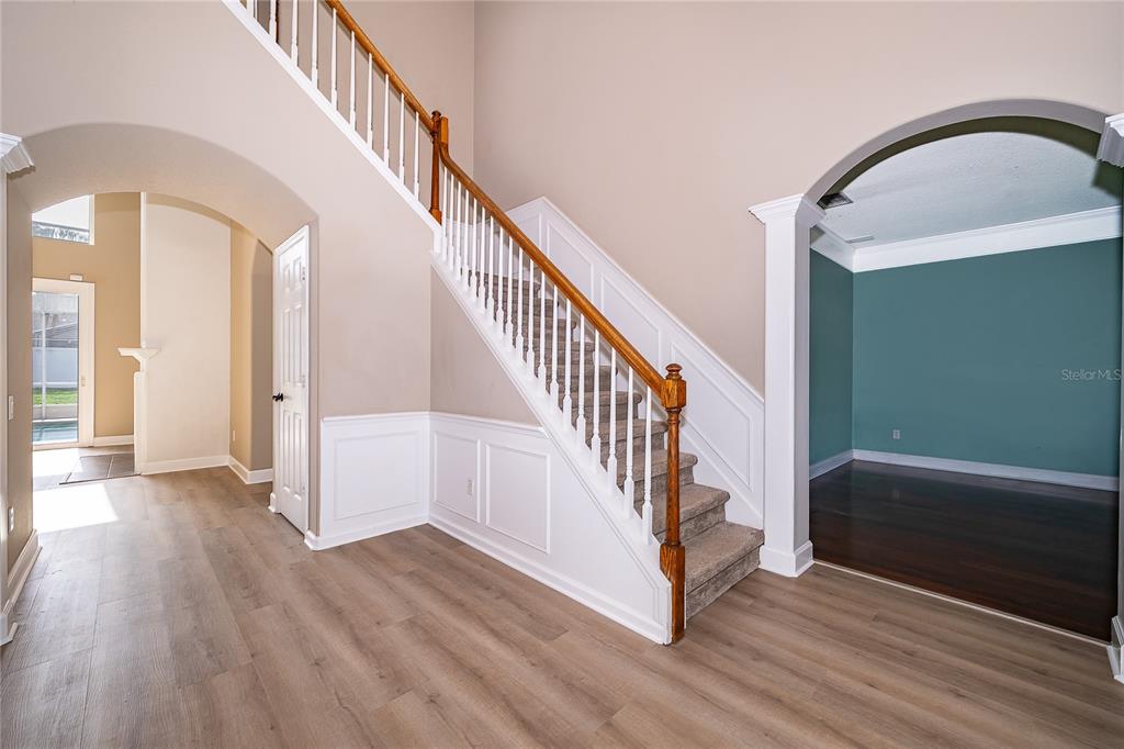An entryway features a staircase with white railings, wood-look flooring, and an arched doorway — 817 HUNTSVILLE ROAD, GOTHA, FL