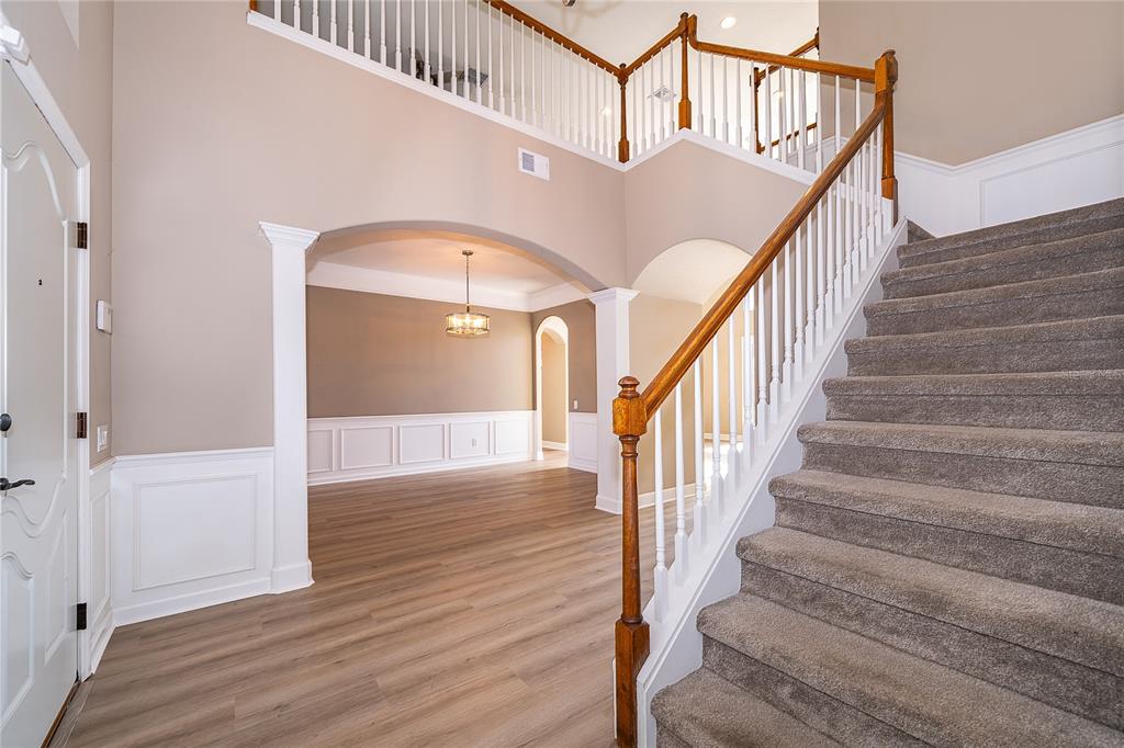 An entryway features a carpeted staircase, wood-look flooring, and an arched opening to a room — 817 HUNTSVILLE ROAD, GOTHA, FL