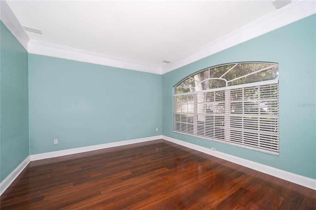 An empty room with teal walls, dark hardwood floors, and a large arched window — 817 HUNTSVILLE ROAD, GOTHA, FL