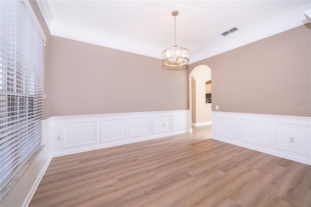 A dining room features light wood flooring, white wainscoting, tan walls, and a drum chandelier — 817 HUNTSVILLE ROAD, GOTHA, FL