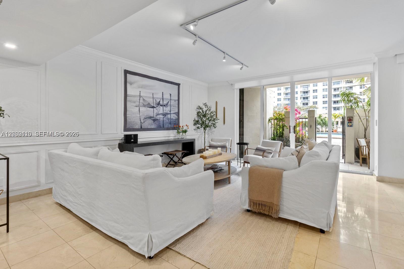 A bright living room features white sofas, a wooden coffee table, and sliding glass doors — 520 Brickell Key Dr # A307, Miami FL 33131, MIAMI, FL