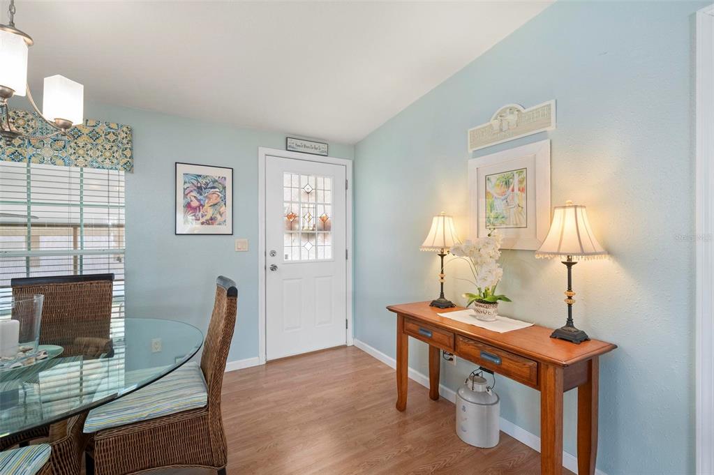 A dining area features a glass table, wicker chairs, light blue walls, and a wooden console — 1000 KINGS HIGHWAY UNIT 487, PORT CHARLOTTE, FL