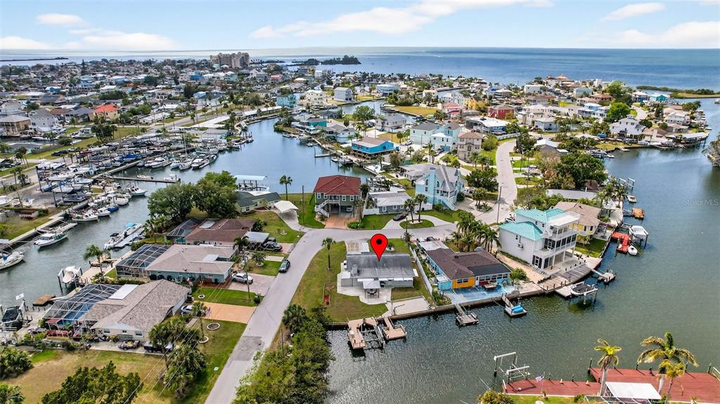 An aerial view shows a waterfront house with a red map pin on a canal — 6645 HARBOR DRIVE, HUDSON, FL