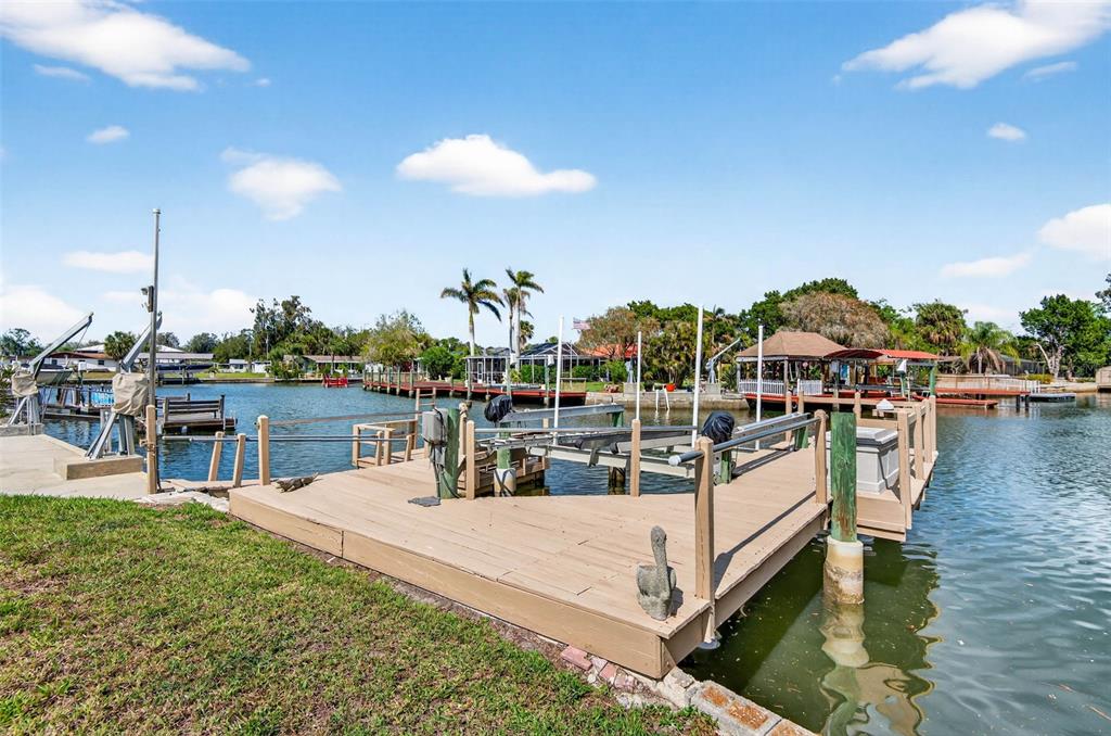 A wooden boat dock with a lift extends into a canal under a blue sky — 6645 HARBOR DRIVE, HUDSON, FL