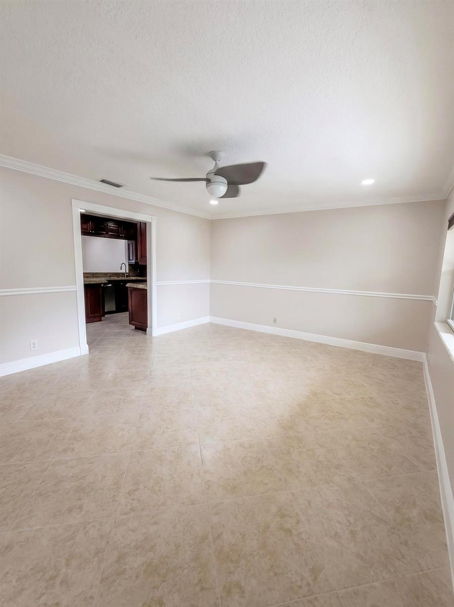 An empty room with beige walls, chair rail molding, tile flooring, and a ceiling fan — 9585 Affirmed Lane, Boca Raton FL 33496, BOCA RATON, FL