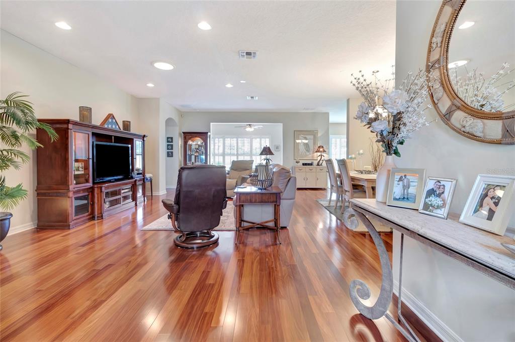 A living room with hardwood floors, a large entertainment center, and a dining area beyond — 3551 CHESSINGTON STREET, CLERMONT, FL