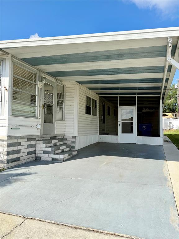 A mobile home exterior features a covered carport, concrete driveway, and white siding — 10399 67TH AVENUE UNIT 4, SEMINOLE, FL