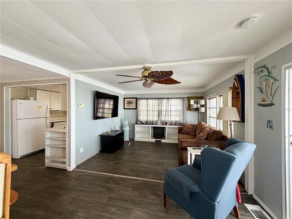 A living room features wood-look flooring, a ceiling fan, a television, and a blue armchair — 10399 67TH AVENUE UNIT 4, SEMINOLE, FL