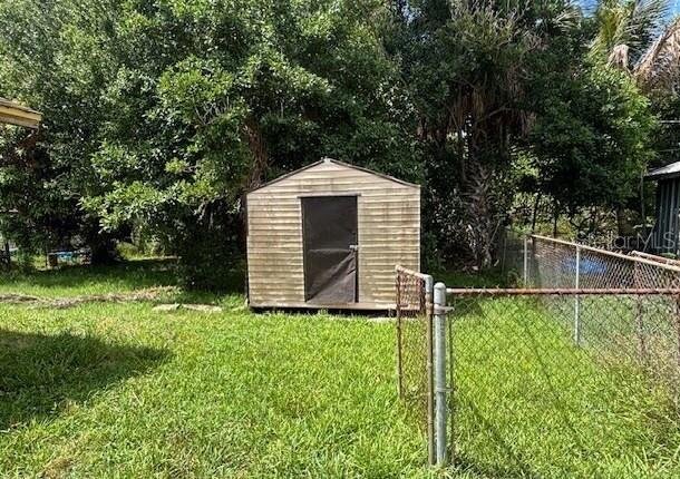 A metal storage shed sits in a grassy backyard next to a chain-link fence — 943 DELLA TOBIAS AVENUE, CLEWISTON, FL