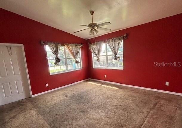 A room with red walls, beige carpeting, a ceiling fan, and two windows with curtains — 943 DELLA TOBIAS AVENUE, CLEWISTON, FL