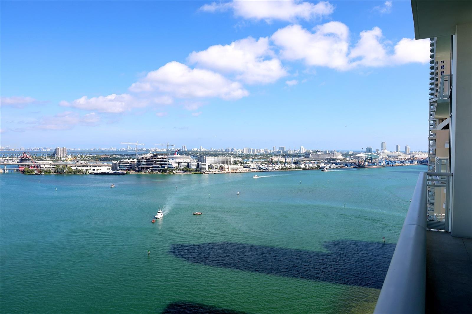 A high-angle view from a balcony overlooking a bay with boats and a city skyline — 900 Brickell Key Blvd # 2002, Miami FL 33131, MIAMI, FL