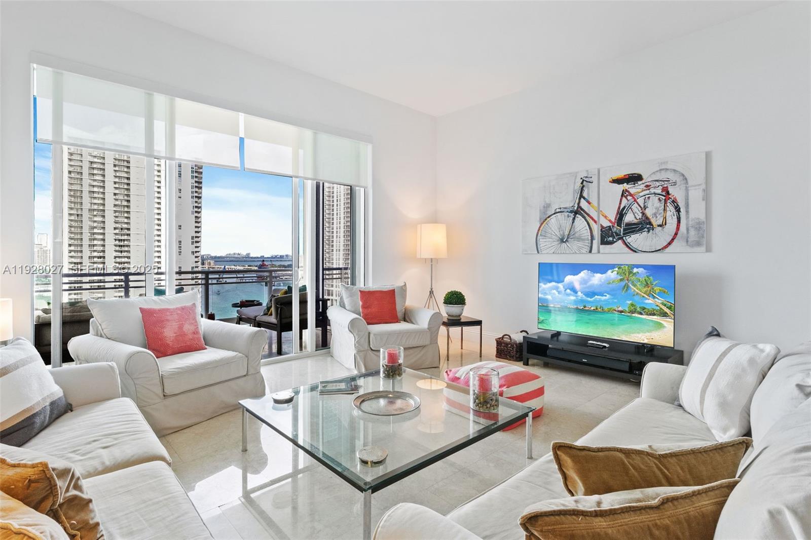 A bright living room features white furniture, a glass coffee table, and a balcony view — 900 Brickell Key Blvd # 2002, Miami FL 33131, MIAMI, FL