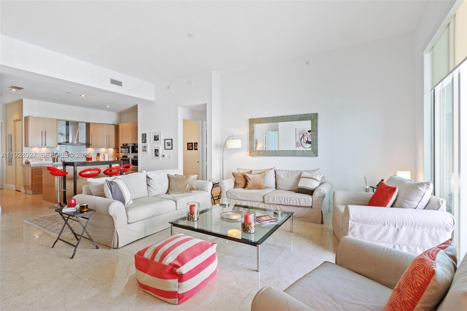 A bright living room features light-colored sofas, a glass coffee table, and an open kitchen — 900 Brickell Key Blvd # 2002, Miami FL 33131, MIAMI, FL