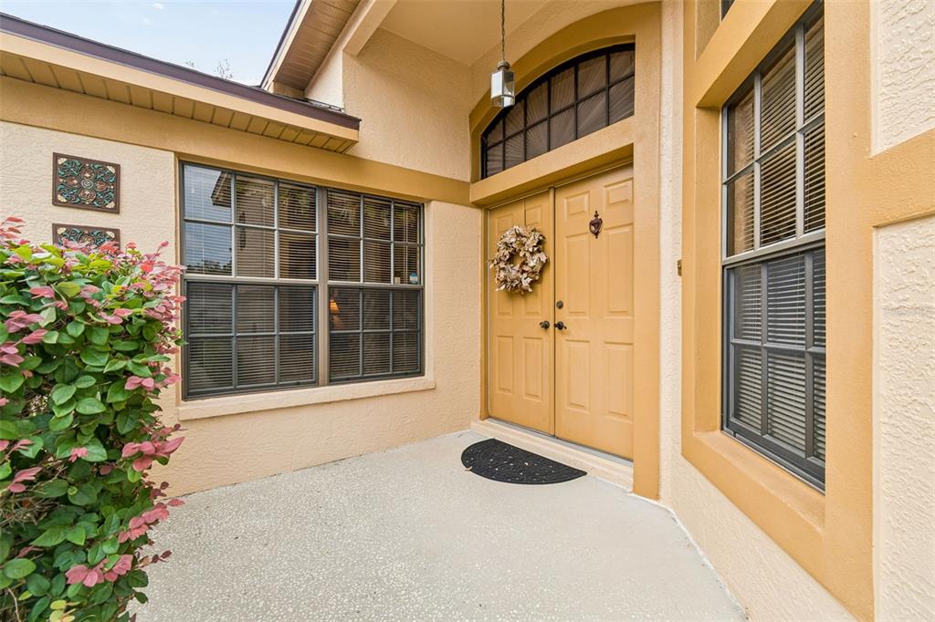 A beige house exterior features a double front door, a concrete porch, and two windows — 9311 HAAS DRIVE, HUDSON, FL