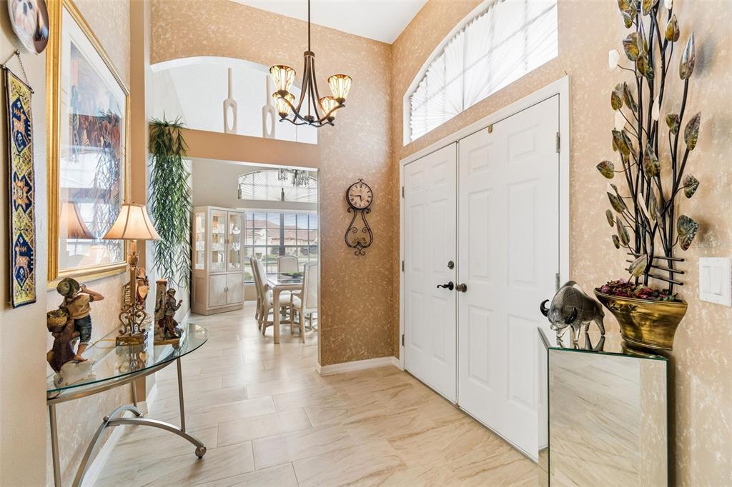 A tiled entryway features a double front door, a chandelier, and a view into a dining room — 9311 HAAS DRIVE, HUDSON, FL
